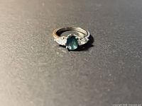 Ring front view showing oval blue-green center stone and side stones