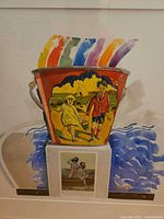 Close-up of artwork showing pail and figure imagery