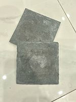 Two black slate coasters front view