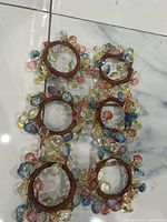 Six brown wrapped napkin rings adorned with translucent yellow, pink and blue beads