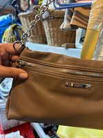 Front view showing brown faux-leather, front zip pocket, Nine West logo plate