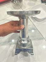 Side view of silver pedestal candle holder showing column and square base