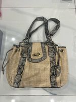 Front view wicker handbag with snakeskin trim and charm