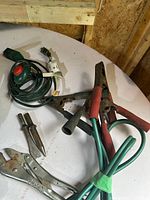 Lot overview showing cord, booster cables, bits, pliers