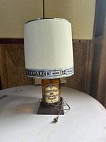 Full view of lamp showing bottle base, wood stand, shade