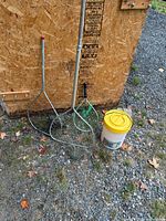 Overall view of three nets and yellow-lid Plano bucket beside shed wall