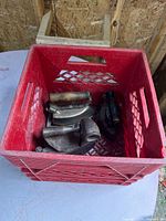 Red milk crate containing multiple antique irons