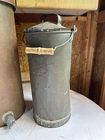 Close-up of milk can showing lid, bail and wood handle