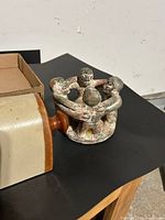 Pottery four-figure candle holder beside end of stoneware foot warmer
