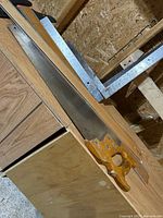 Hand saw and metal square on wooden surface