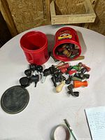 Two red tubs, loose handles, caster wheels and tub lid on table