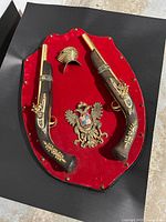 Full view of plaque with both pistols, coat of arms and helmet crest