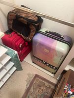 bebe hard-shell suitcase, two stacked red rolling suitcases, brown duffel