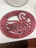 Red cast iron swan trivet showing paint wear