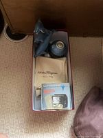 Box containing dolphin figurine, Ferragamo dust bag, Lumiscope alarm clock