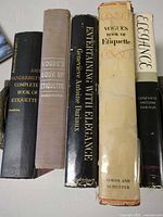 Spines of all five hardcover etiquette books visible upright on table