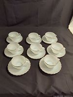 Eight cup and saucer sets arranged on dark cloth