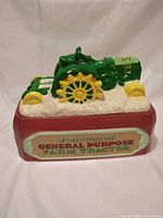 Top view of ceramic cookie jar featuring green John Deere tractor on red base