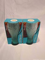 Front view of two boxed Coca-Cola contour glasses
