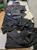 Multiple dark garments spread on table