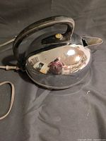 Left side view of chrome GE electric kettle showing handle, power cord and overall condition