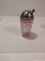 Full view of glass cocktail shaker with printed graphics and metal lid