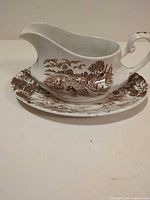side view of gravy boat on underplate showing scenic pattern