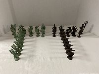 Full set of verdigris and dark patina brass chess pieces aligned in two rows per side