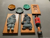 Group shot of all seven items—RCMP statue, three wood plaques, three ceramic dishes