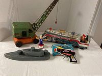 Group shot of all five toys: crane truck, tin train, boxed spark gun, wooden submarine, Popeye figure