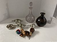 Group shot showing all items: decanter, stoneware bottle, three cups, jigger, four stoppers