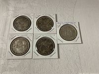 Front view of five silver dollars in 2×2 flips, obverse side visible