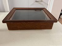 Side view of closed wooden display case showing glass top and wood frame