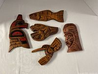 Five carved plaques arranged on white surface