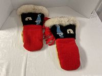 Front view showing red wool backs, black cuffs with appliqué, fur trim