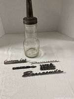 Full view oil bottle with spout and five emblems on table