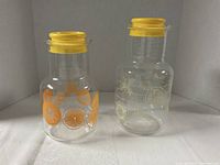 Both Pyrex pitchers side by side showing citrus graphics and lids