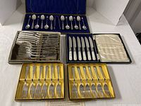 All five presentation boxes open showing teaspoons, dinner forks, dinner knives, two boxes of pastry forks