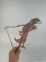 Full view of the Balinese leather shadow puppet held upright showing painted detail and control rods