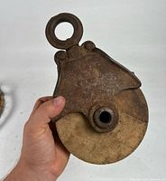 Front view of cast iron and wood pulley held in hand, LOUDEN marking visible