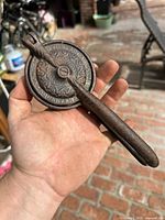 Full view of closed cast iron lemon squeezer showing ornate disc and handle