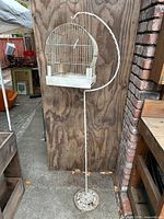 Full view of birdcage hanging on wrought iron floor stand