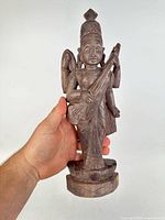 Front view of carved rosewood goddess statue in hand for scale