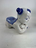 Front angled view showing child figure reclining, blue garment detail