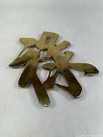 Front view of solid brass openwork Chinese character trivet
