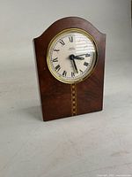 Front view of wood veneer mantel clock showing dial and inlay