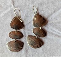 Close-up of hammered sterling dangle earrings with 925 mark