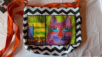 Front of small canvas bag with cat motif and orange strap