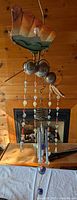Full view of hanging wind chime showing bird motif, bead strands and chime tubes