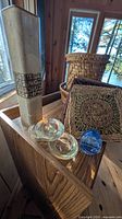 Shelf top with ceramic vase, glass votives, blue glass egg, woven hot pads, tall wicker basket
